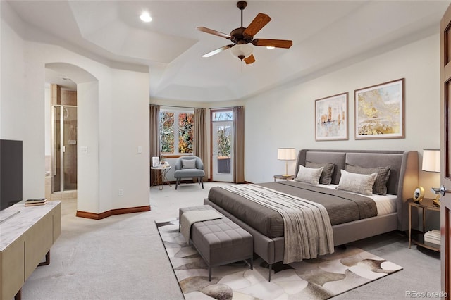 carpeted bedroom featuring ceiling fan, a tray ceiling, and connected bathroom