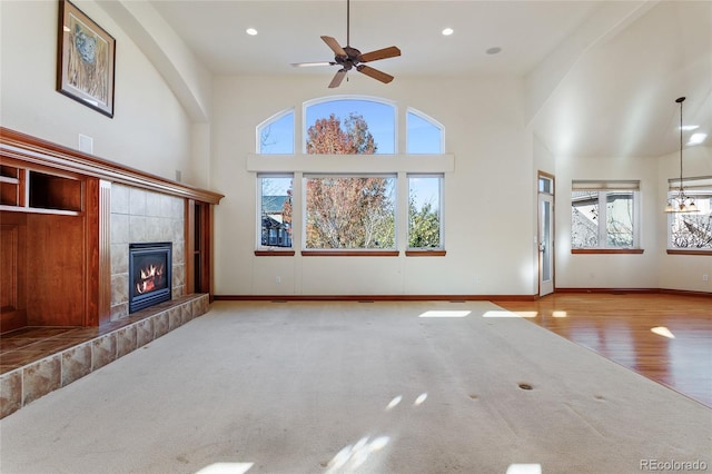 unfurnished living room featuring a healthy amount of sunlight, a towering ceiling, and a tiled fireplace