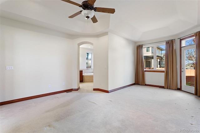 carpeted empty room featuring a raised ceiling and ceiling fan