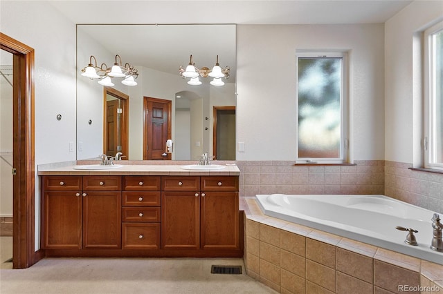 bathroom featuring vanity and a relaxing tiled tub