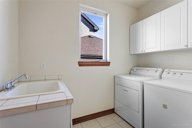 laundry area featuring light tile patterned floors, washing machine and dryer, sink, and cabinets