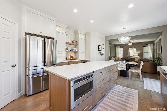 13463 Tamarac Pl, Thornton, CO 80602 - kitchen with stainless steel appliances, wood finished floors, a chandelier, a kitchen island, and recessed lighting