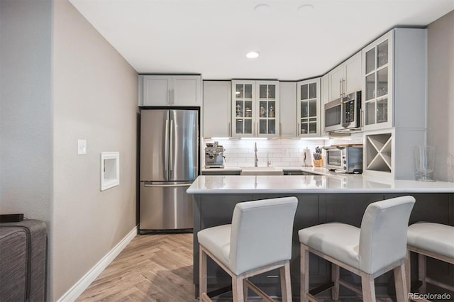 13463 Tamarac Pl, Thornton, CO 80602 - kitchen with appliances with stainless steel finishes, a kitchen bar, tasteful backsplash, a peninsula, and light countertops