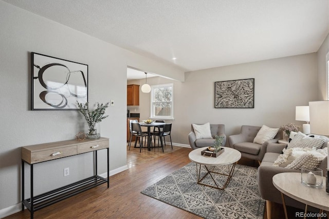 living room featuring a textured ceiling, baseboards, and wood finished floors