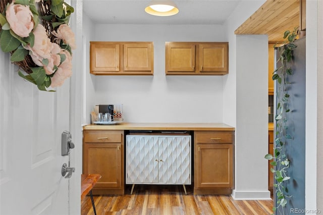bar featuring a bar, light wood finished floors, and dishwasher