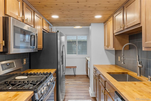 kitchen with butcher block countertops, a sink, wood ceiling, and stainless steel appliances