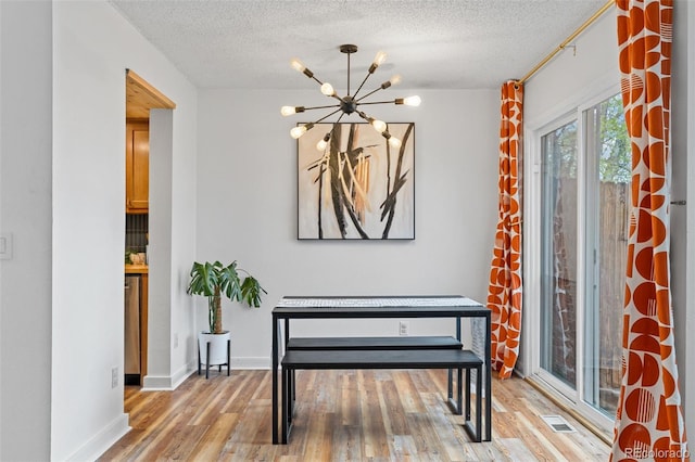 foyer with a textured ceiling, an inviting chandelier, and light wood-style floors