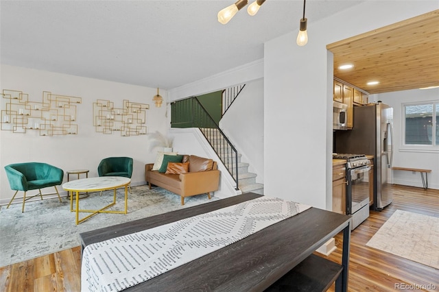 living area featuring baseboards, stairs, and wood finished floors