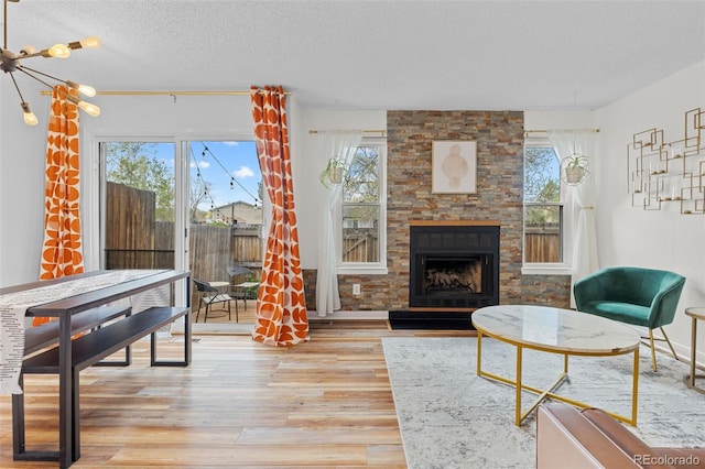 living room with a textured ceiling, light wood-style flooring, and a fireplace