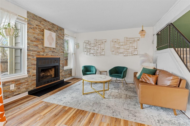 living area featuring stairway, baseboards, a fireplace, and wood finished floors
