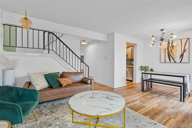 living room with stairs, baseboards, a textured ceiling, and wood finished floors