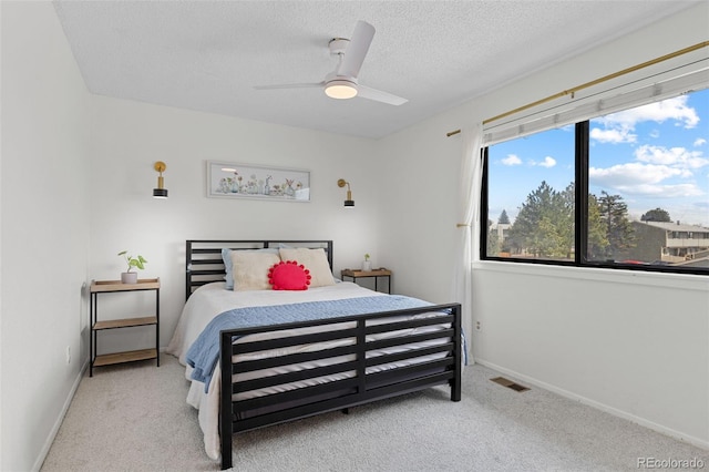 carpeted bedroom featuring baseboards, ceiling fan, a textured ceiling, and visible vents