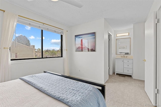 bedroom featuring light colored carpet, a sink, a textured ceiling, a ceiling fan, and baseboards