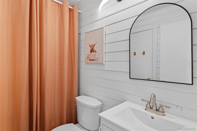 bathroom featuring toilet, wood walls, a shower with shower curtain, and vanity