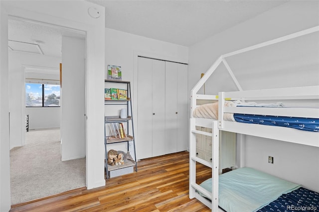 bedroom featuring wood finished floors, attic access, and a closet