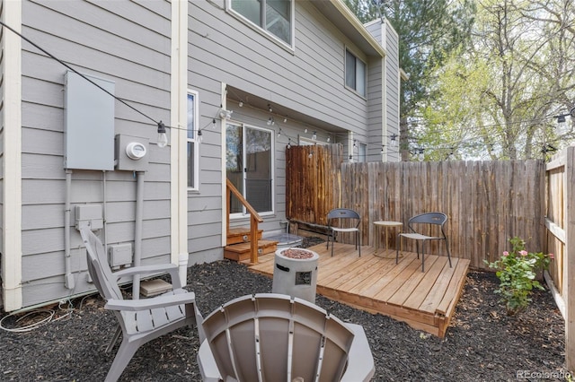 view of patio / terrace with fence, a wooden deck, entry steps, and an outdoor fire pit