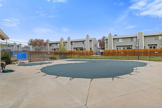 community pool featuring a patio, fence, and a residential view
