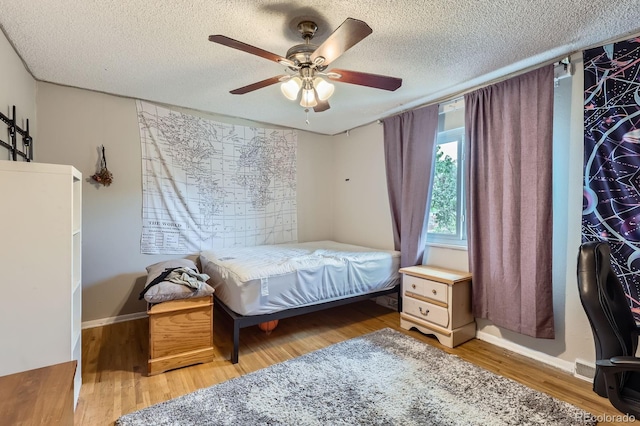 bedroom featuring wood finished floors, a textured ceiling, a ceiling fan, and baseboards