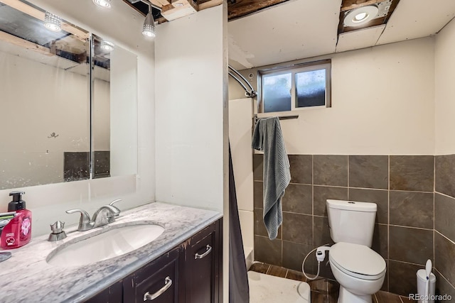 full bathroom featuring a shower, vanity, tile walls, toilet, and a wainscoted wall