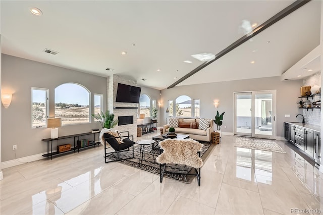 living room featuring a stone fireplace, vaulted ceiling, and a healthy amount of sunlight