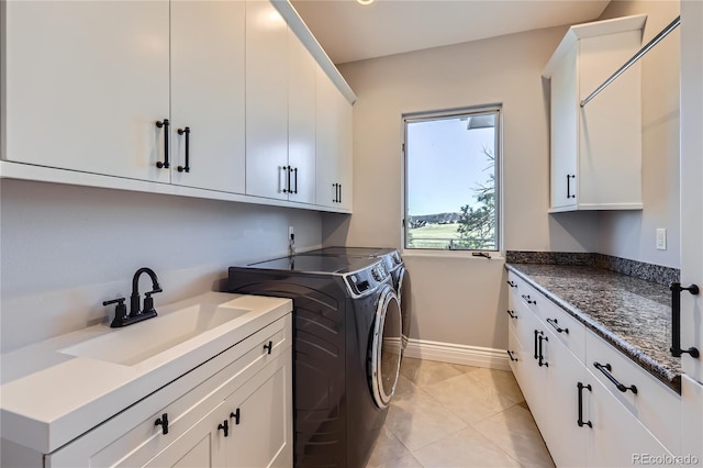 clothes washing area featuring sink, light tile patterned floors, washer and clothes dryer, and cabinets