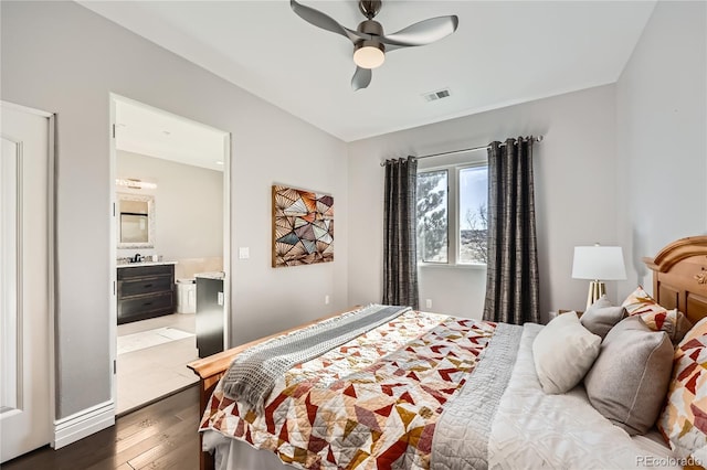 bedroom with dark wood-type flooring, ceiling fan, and connected bathroom