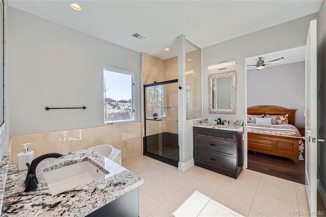 bathroom with walk in shower, tile walls, vanity, ceiling fan, and tile patterned flooring