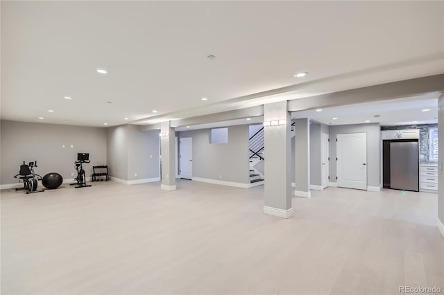 basement featuring stainless steel fridge and light hardwood / wood-style floors