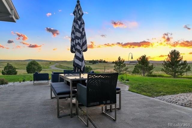 patio terrace at dusk with a yard and a rural view