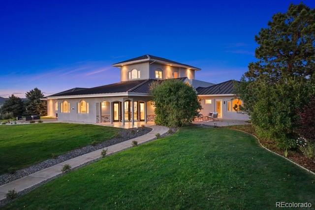 back house at dusk with a lawn