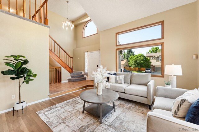 11932 W 56th Cir, Arvada, CO 80002 - living room with stairs, a towering ceiling, light wood-type flooring, and a chandelier