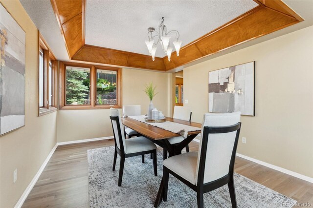 11932 W 56th Cir, Arvada, CO 80002 - dining space with a chandelier, wood finished floors, a raised ceiling, and a textured ceiling