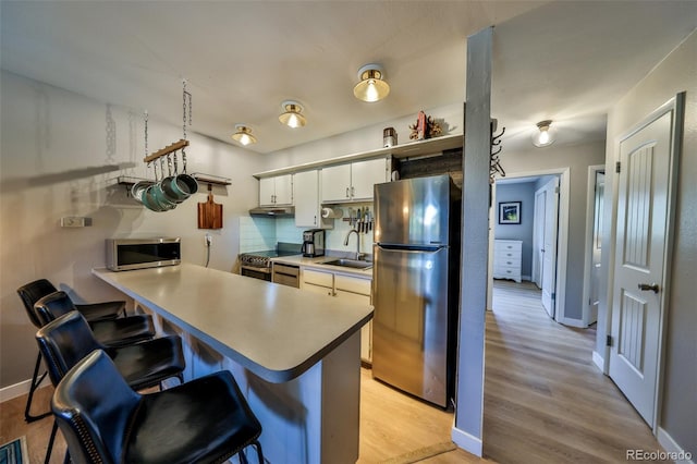 466 Hi Country Dr Unit 109, Winter Park, CO 80482 - kitchen featuring appliances with stainless steel finishes, a breakfast bar, light wood finished floors, a peninsula, and light countertops