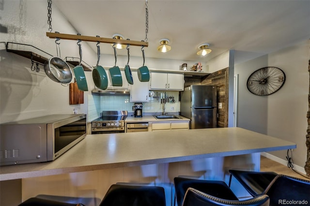 466 Hi Country Dr Unit 109, Winter Park, CO 80482 - kitchen featuring appliances with stainless steel finishes, under cabinet range hood, tasteful backsplash, a kitchen breakfast bar, and a peninsula