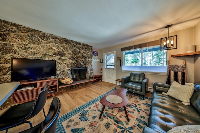 466 Hi Country Dr Unit 109, Winter Park, CO 80482 - living room featuring wood finished floors, a chandelier, a stone fireplace, and a baseboard radiator