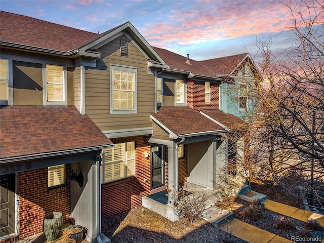 view of front of house featuring a shingled roof and brick siding