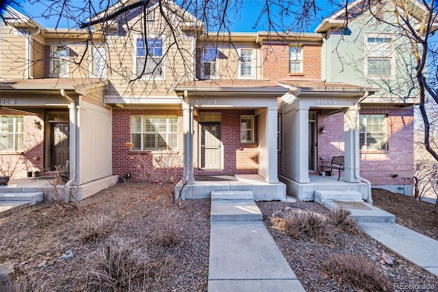 townhome / multi-family property with brick siding and a porch