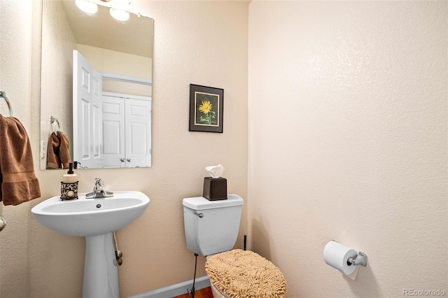 bathroom featuring baseboards, a sink, and toilet