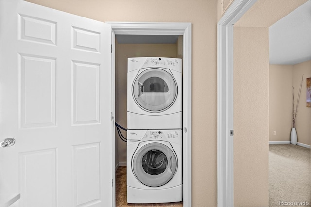 washroom with carpet, laundry area, baseboards, and stacked washing maching and dryer