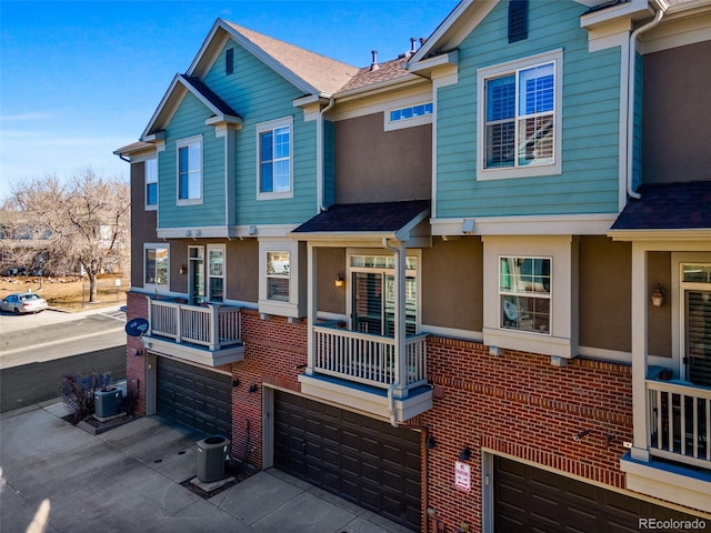 multi unit property with stucco siding, central AC unit, and brick siding