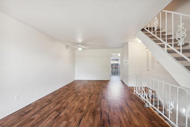 unfurnished living room featuring ceiling fan and dark wood-type flooring