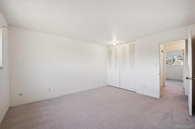 unfurnished bedroom featuring light carpet and a closet