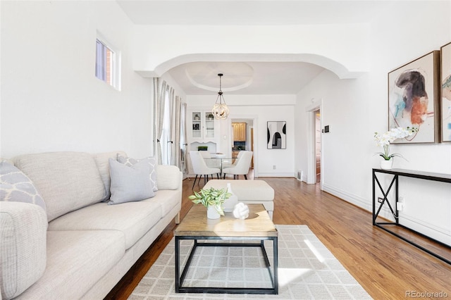 living room featuring baseboards, arched walkways, and wood finished floors