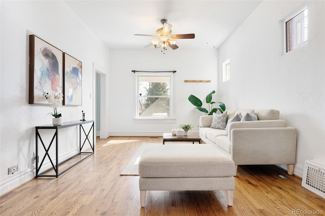 living area featuring visible vents, baseboards, a ceiling fan, and light wood finished floors