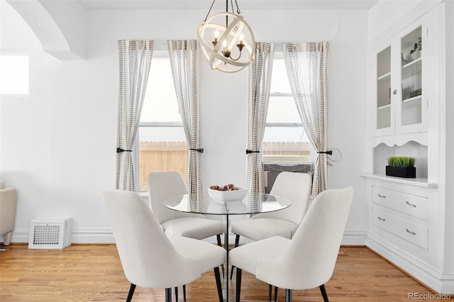 dining room featuring baseboards, light wood-type flooring, and an inviting chandelier