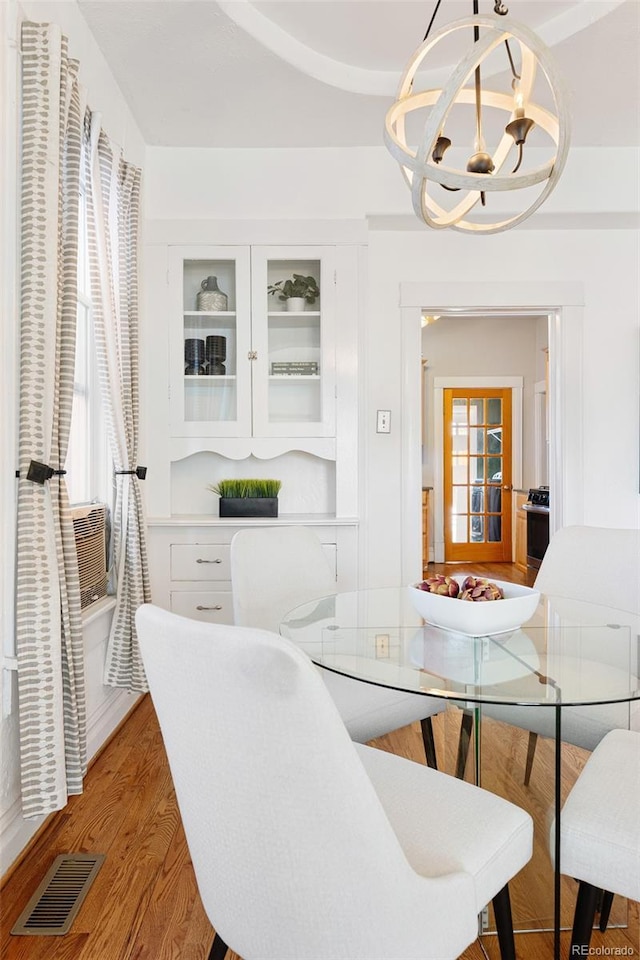 dining space featuring a chandelier, visible vents, cooling unit, and light wood-style floors