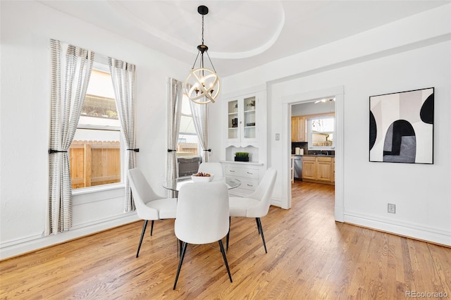 dining room featuring a chandelier, baseboards, and light wood-style floors