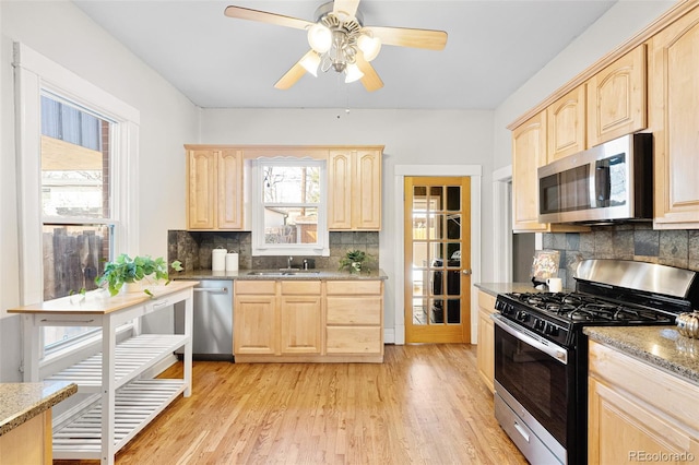 kitchen with a sink, stainless steel appliances, light wood-style floors, and light brown cabinetry