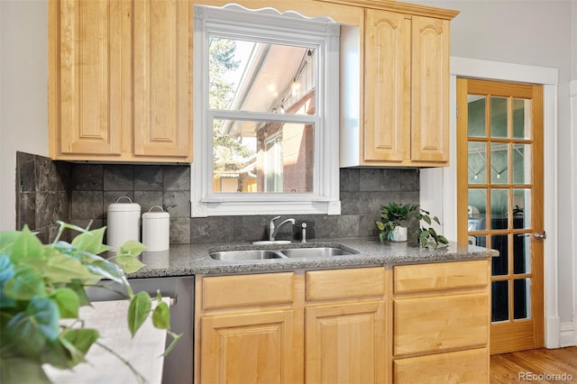 kitchen with tasteful backsplash, light brown cabinets, dishwasher, stone countertops, and a sink