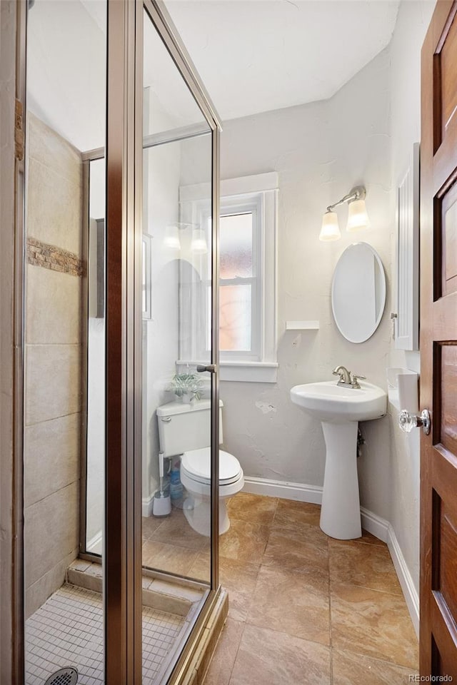 bathroom featuring a shower stall, toilet, and baseboards